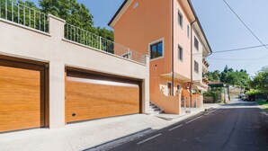 Um prédio residencial de dois andares com garagem, varanda e vista para a rua.