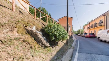 Una strada residenziale fiancheggiata da case, cielo sereno e una strada con auto parcheggiate a bordo.