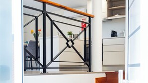 Una escala de fusta amb barana metàl·lica que porta a un espai amb cuina.