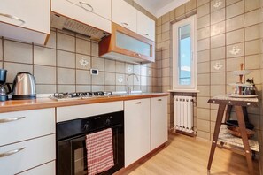 Eine moderne Küche mit Gasherd, Backofen und einem Fenster über der Spüle.