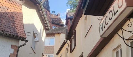 A narrow cobblestone street flanked by buildings with signage, including 'VICOLLO'.