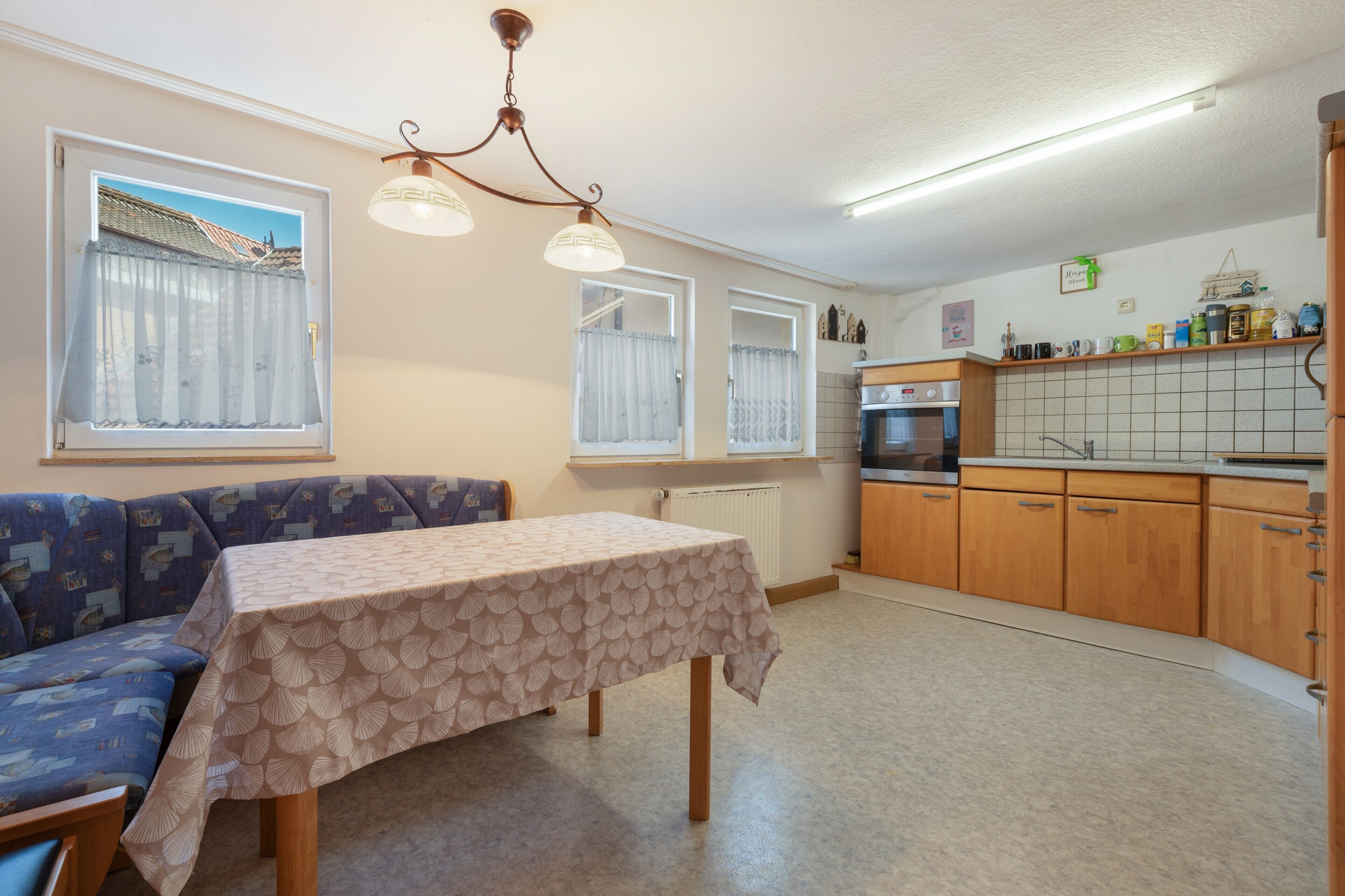 Una cocina compacta con comedor, un sofá y una mesa con mantel.