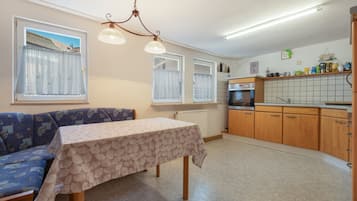 Una cocina compacta con comedor, un sofá y una mesa con mantel.