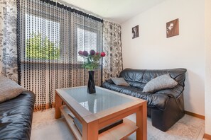 Uma sala de estar com um sofá de couro, uma mesa de centro de vidro e um vaso com flores.