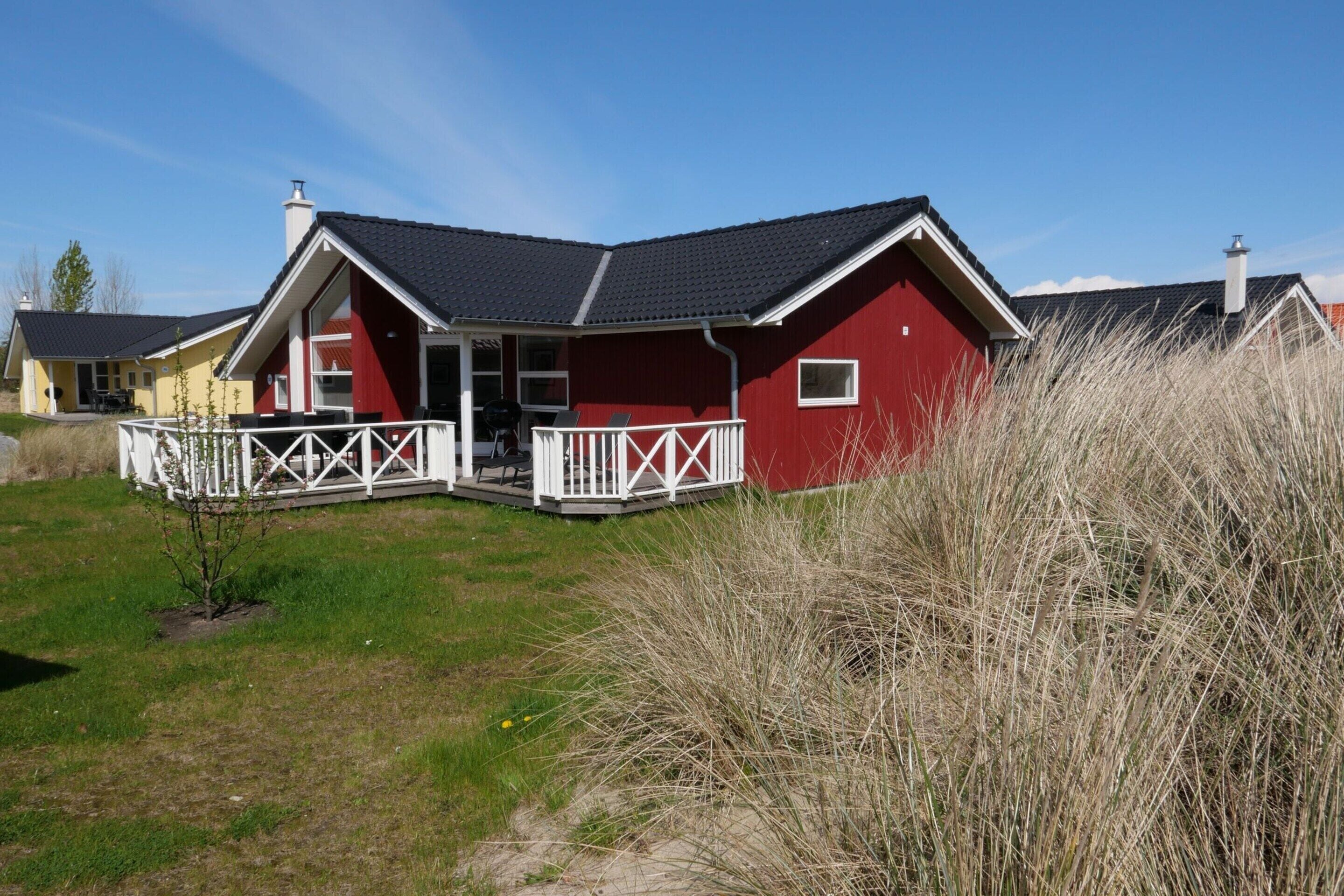 A red house with a porch and a small garden.
