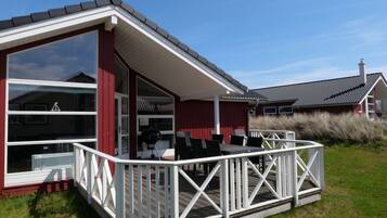 A house with a covered patio, a barbecue grill, and a deck with chairs.