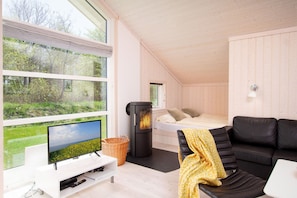 Ein modernes Interieur mit einem großen Fenster, einem schwarzen Sofa, einem Bett und einem Kamin.