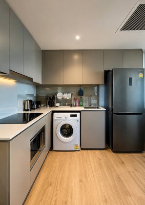 Eine kleine Küche mit Waschmaschine, Kühlschrank und Spüle.