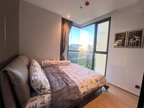 A bedroom with a large window, a bed with patterned bedding, and two wall-mounted animal-themed decorations. - 2 Bed Room Rare Unit With Bath Tub Sea View (Pattaya)