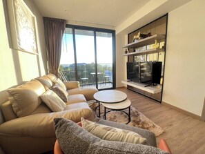 Ein modernes Wohnzimmer mit einer Couch, einem runden Tisch und einem Fernseher an einem Regal.