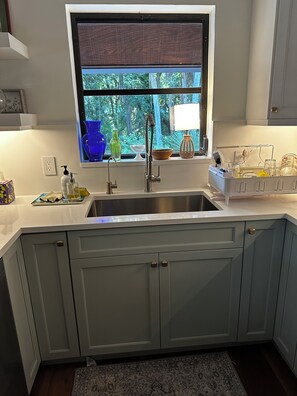 A kitchen with a window, a sink, cabinets, and various kitchen items on the counter. - Beautiful, private Florida home surrounded with tropical forest in Jupiter farms (Jupiter)