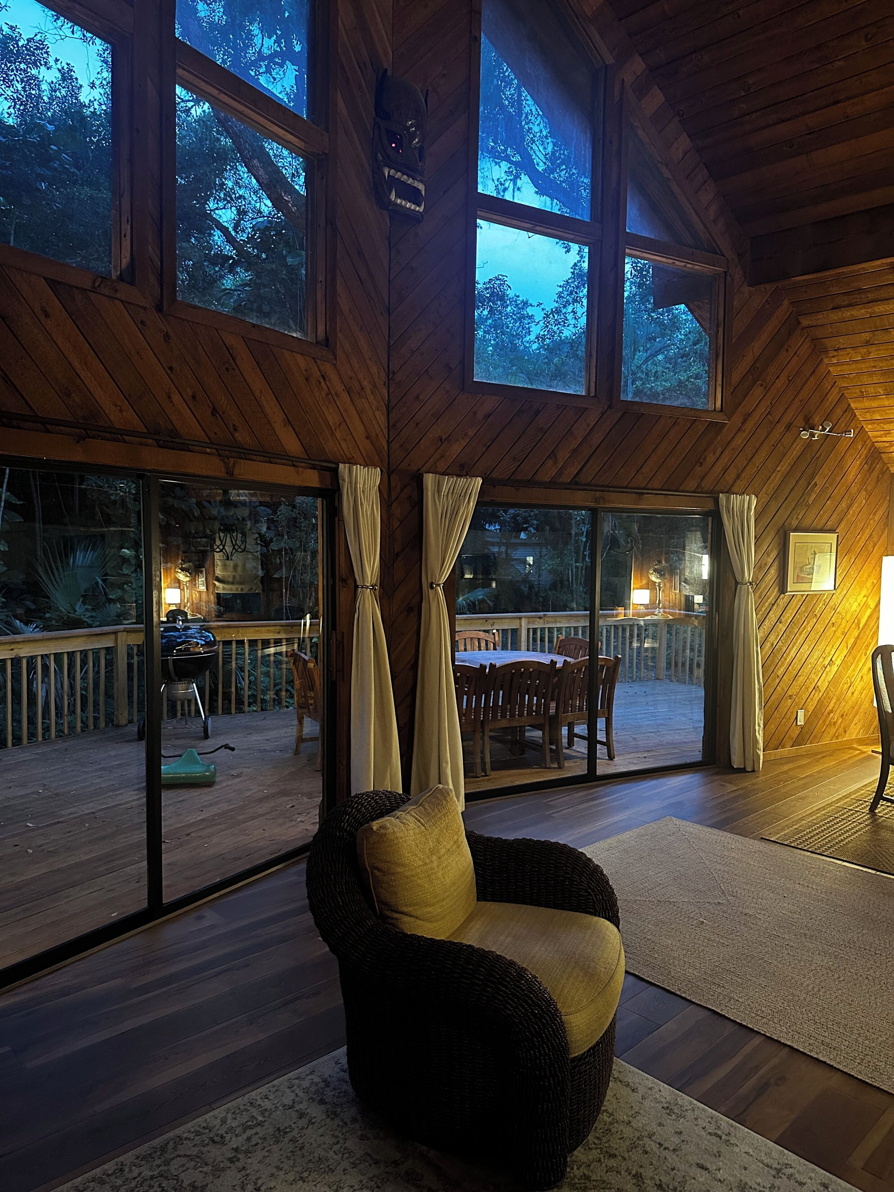 A cozy room with a large window, a wooden ceiling, and a view of the outdoors.