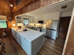 A modern kitchen with a central island, stainless steel appliances, and wooden paneling.