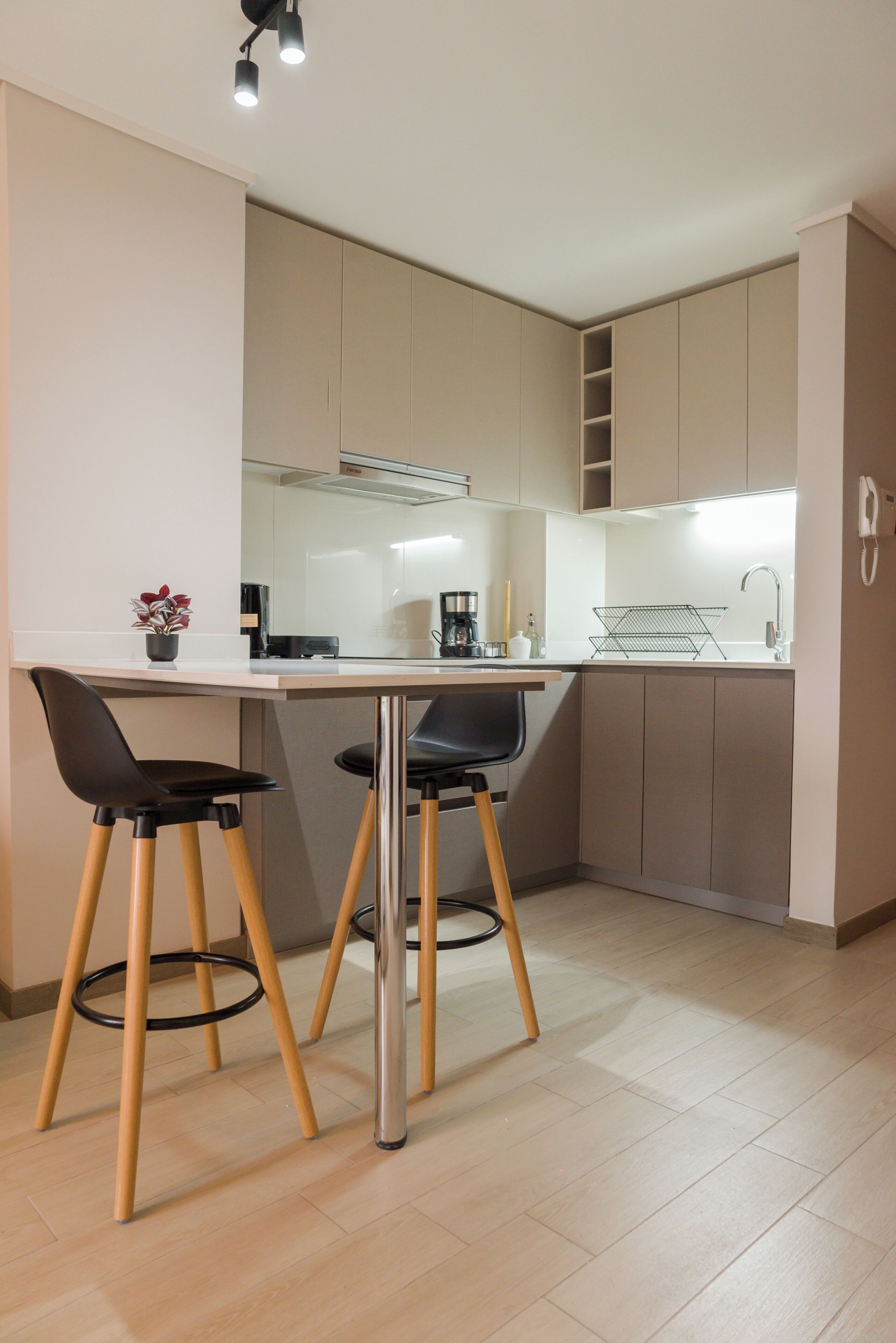 Een moderne keuken met een eethoek, voorzien van een keukeneiland met krukken, een koffieapparaat en een inbouwoven.