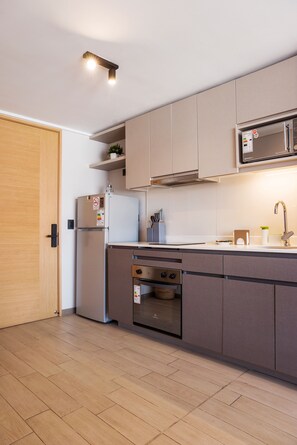 A modern kitchen with a built-in oven, a microwave, and a sink. - Brown Sur Apartments by Andes STR (Ñuñoa)