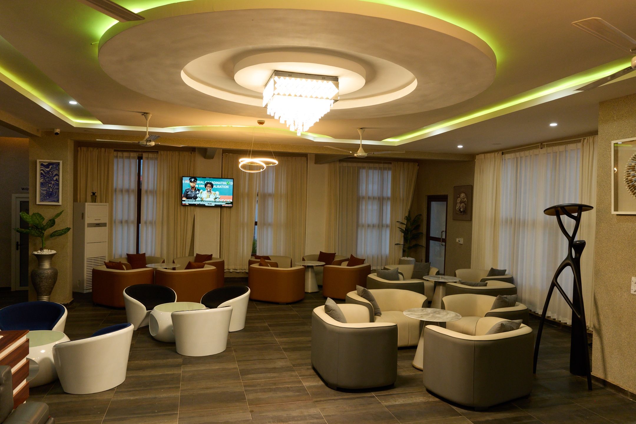 A hotel lobby with modern seating, a television, and a chandelier.