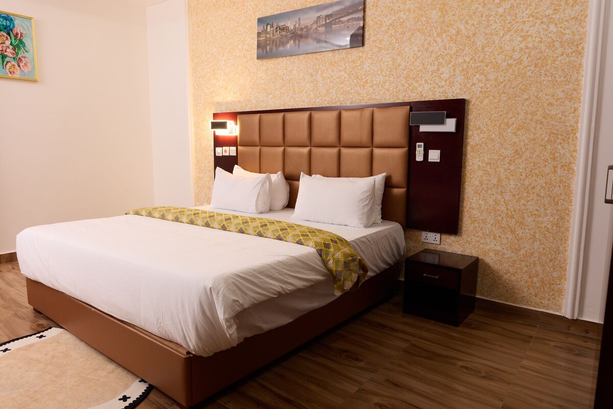 Una habitación de hotel con una cama grande, una mesita de noche, un teléfono en la pared y un cuadro.
