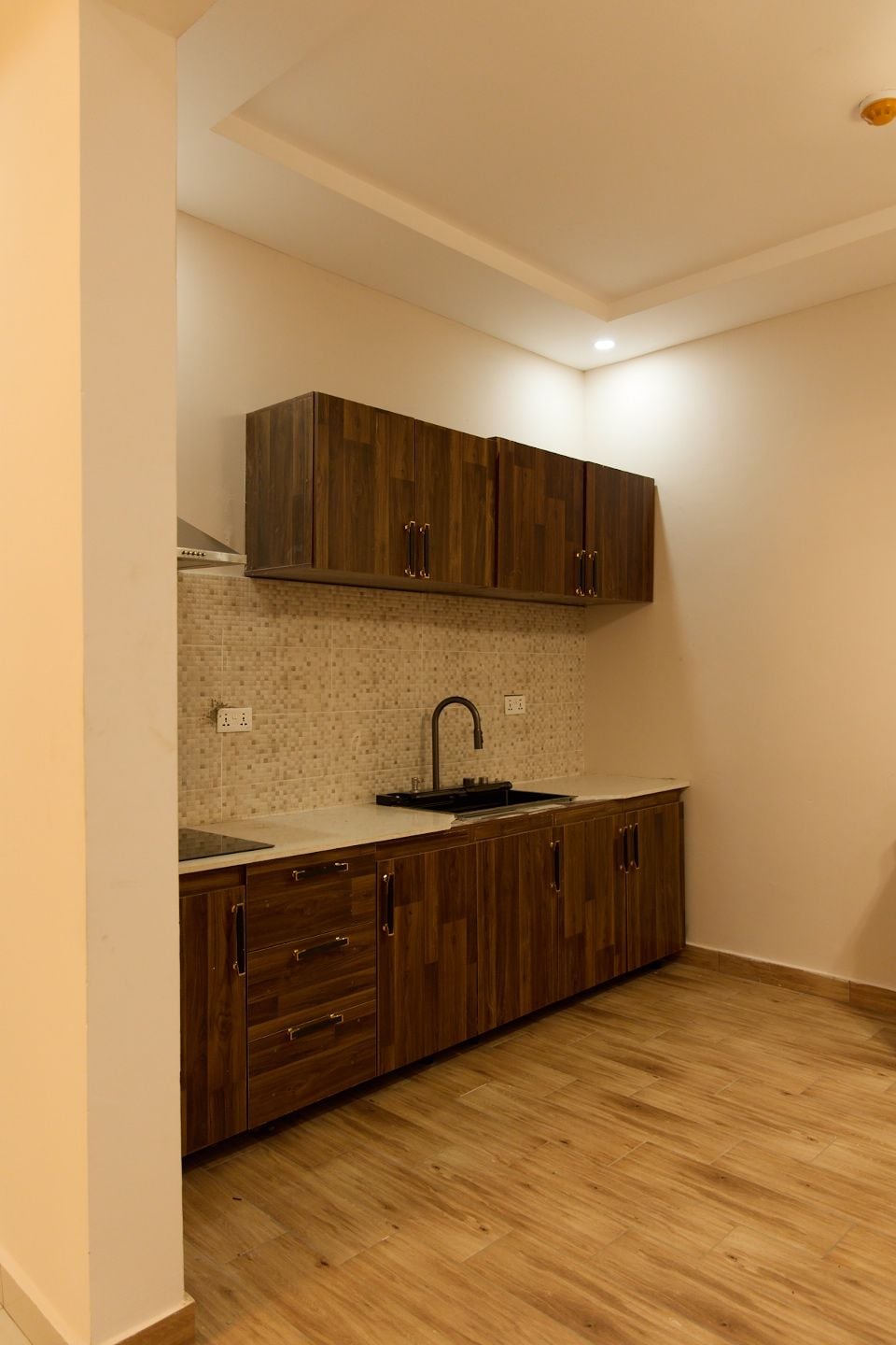A compact kitchen with wooden cabinets, a tiled backsplash, and a single sink.