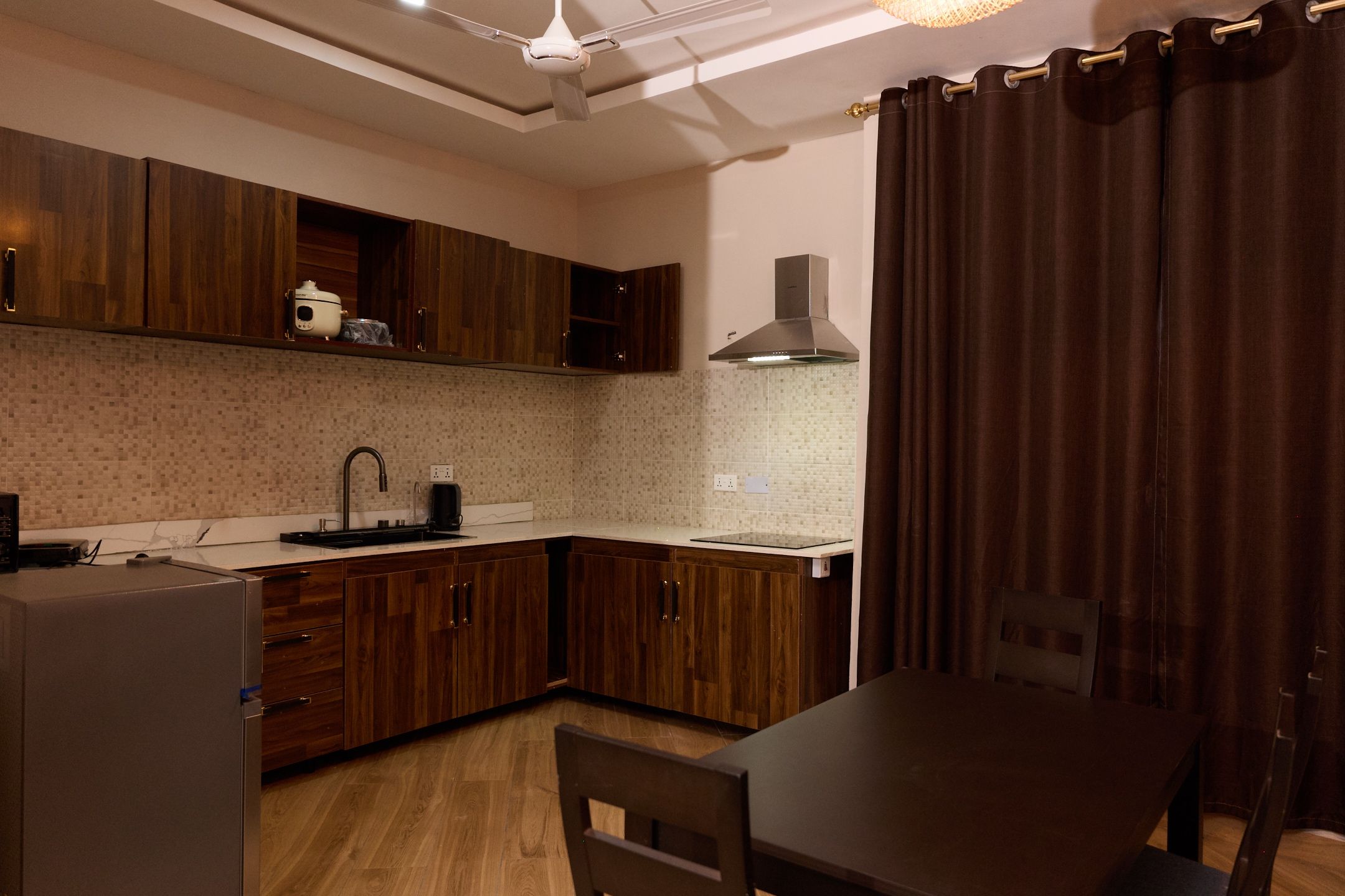 Une cuisine moderne avec des meubles en bois, un four encastré, un évier et un coin repas comprenant une table et des chaises.