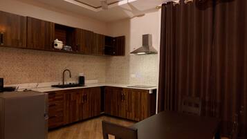 Une cuisine moderne avec des meubles en bois, un four encastré, un évier et un coin repas comprenant une table et des chaises.