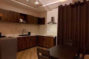 A modern kitchen with wooden cabinets, a built-in oven, a sink, and a dining area with a table and chairs.