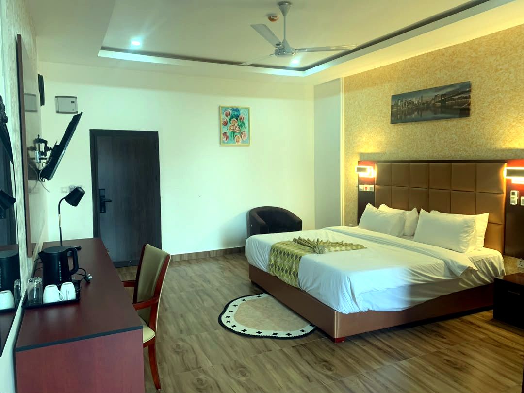 A hotel room with a bed, desk, chair, and a ceiling fan.
