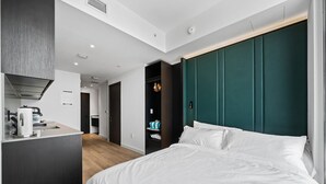 Een moderne hotelkamer met een bed, een bureau met waterkoker en een kledingkast.