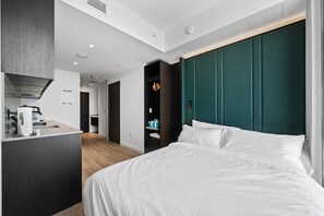 Ein modernes Hotelzimmer mit Bett, Schreibtisch mit Wasserkocher und Kleiderschrank.
