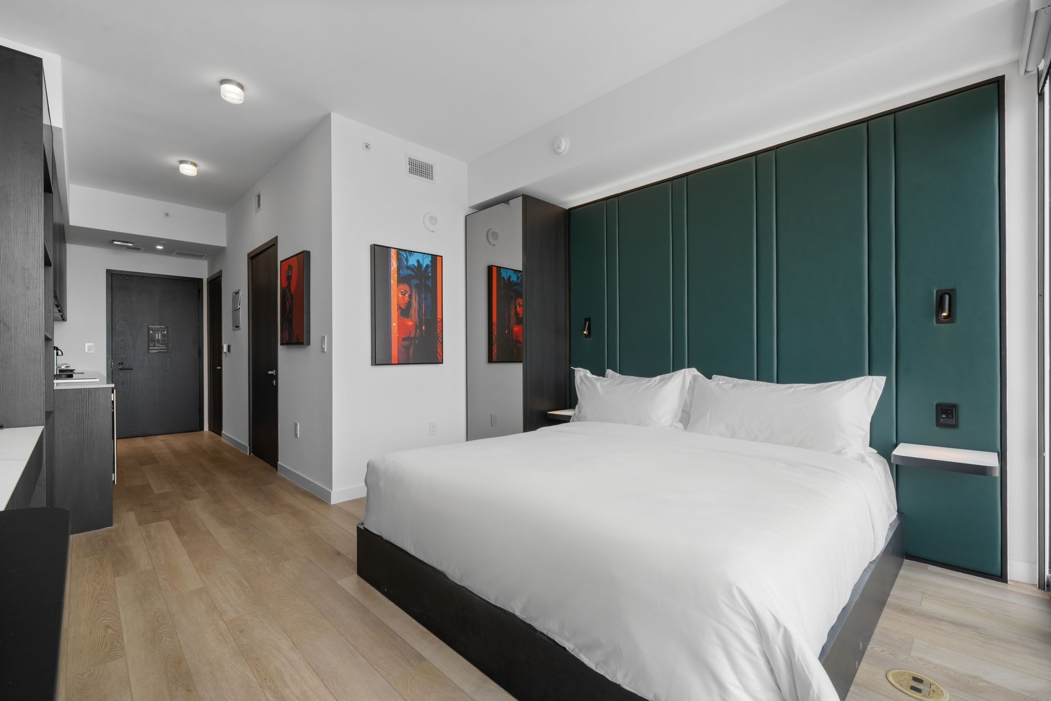Een moderne hotelkamer met een groot bed, een bureau en kunstwerken aan de muur.