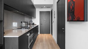 A modern kitchen with dark cabinetry, stainless steel appliances, and a wooden floor. - E11EVEN Studio Suite w/ Rooftop Pool City Views (Miami)