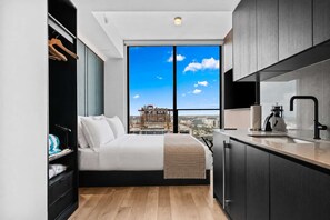A modern bedroom with a city view, a bed, a wardrobe, and a kitchenette. - Stunning Studio Suite At The E11EVEN Residences (Miami)