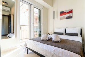 Ein Hotelzimmer mit Bett, Nachttisch, Wandbild und einer Schiebeglasdoor zum Balkon.