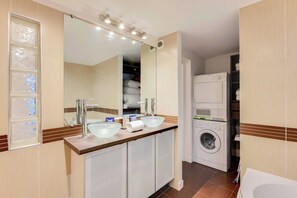 A bathroom with a double sink, a mirror, a washing machine, and a toilet. - Parisian Duplex 1br/6p - in the Heart of the Marais (Paris)