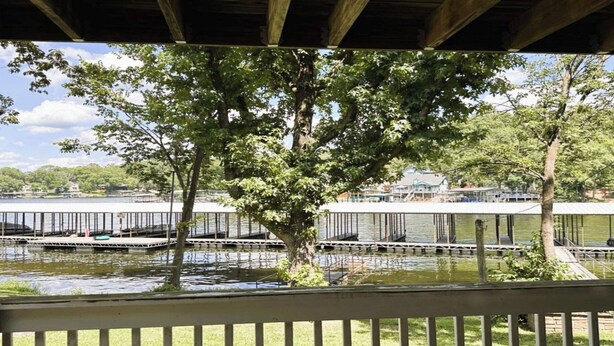 A view of a waterfront property with a dock, trees, and a building in the background.