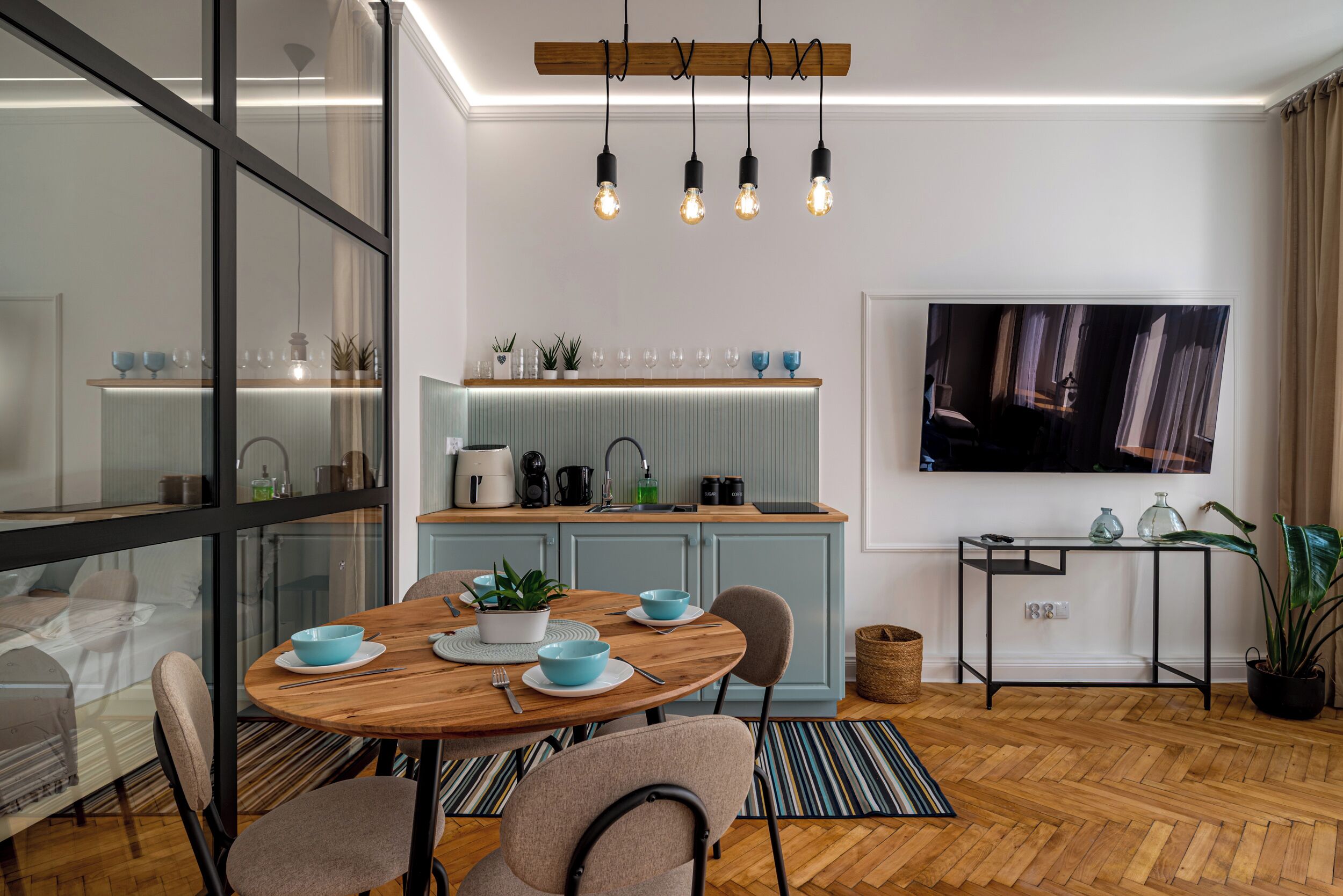 Una cocina moderna con comedor, piso de madera y televisor montado en la pared.