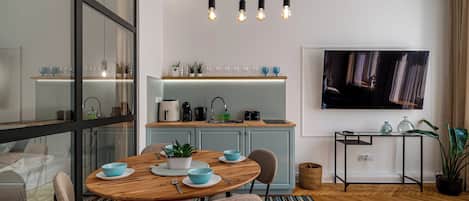 Una cocina moderna con comedor, piso de madera y televisor montado en la pared.