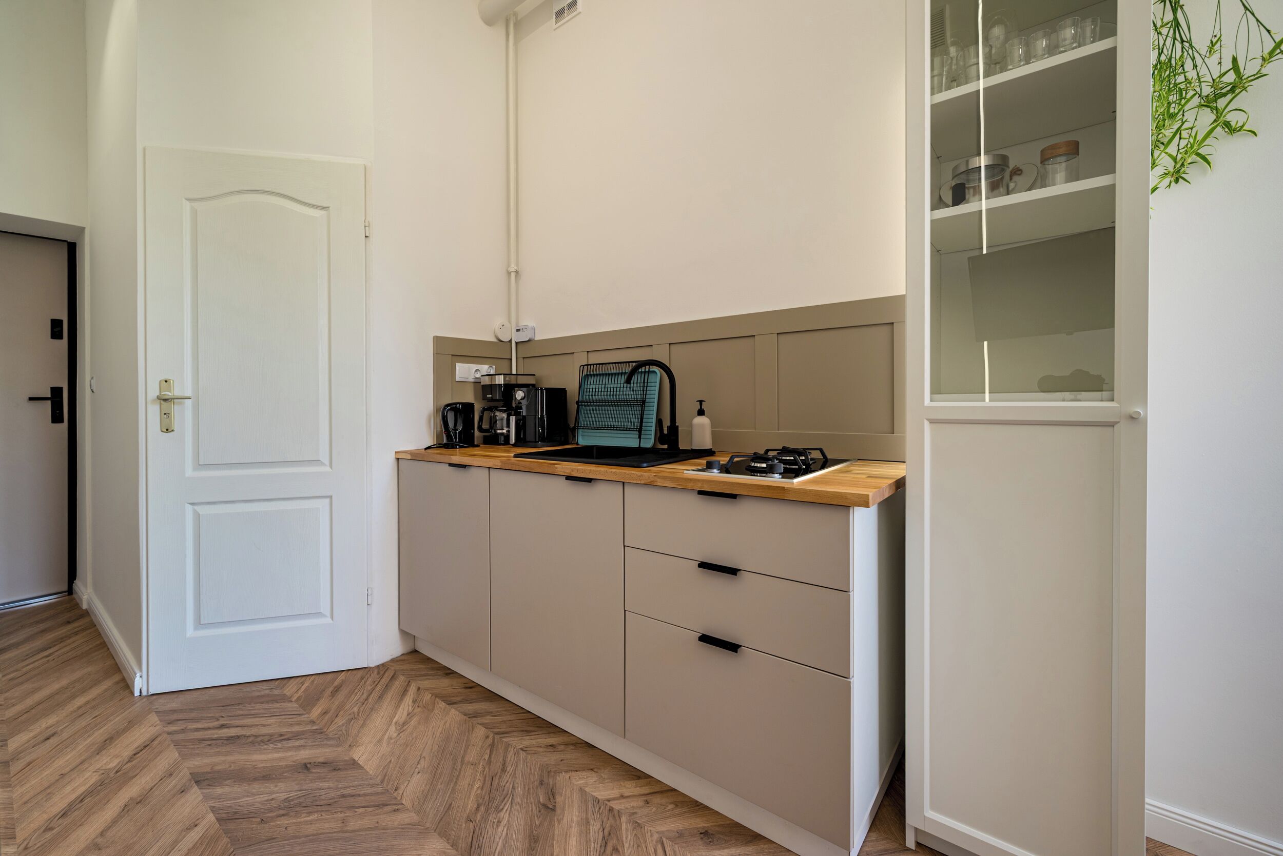 Una cocina compacta con estufa a gas integrada, cafetera y lavavajillas.