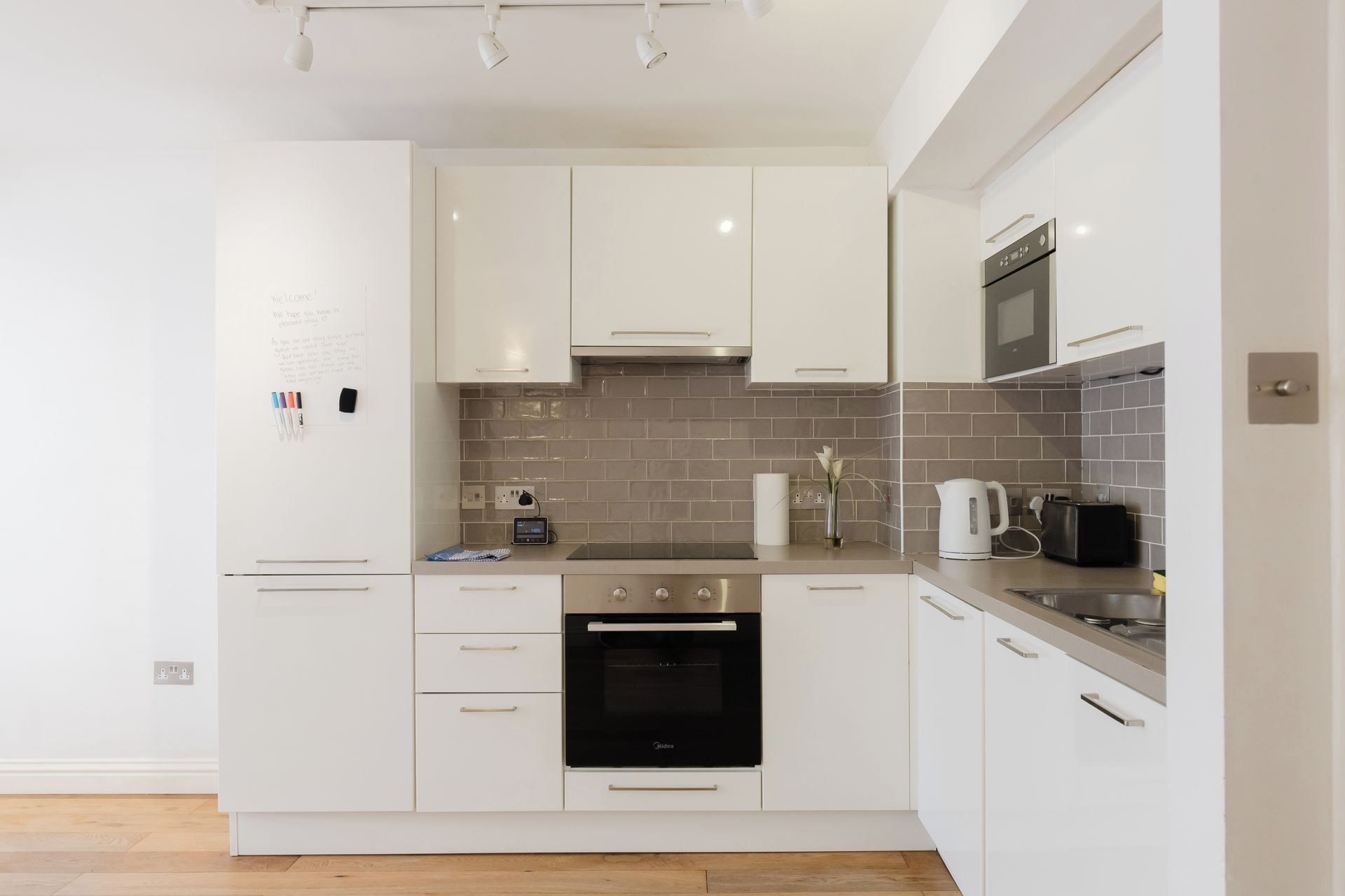 A modern kitchen with white cabinets, a black oven, a microwave, and a coffee maker.