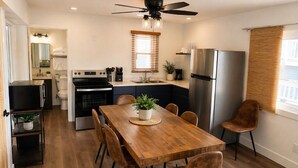 A compact kitchen with a dining area, a ceiling fan, and a refrigerator.
