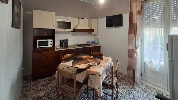 A compact kitchen with a dining table, chairs, a microwave, and a TV mounted on the wall.