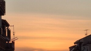 A sunset over a residential area with buildings on either side of a street.