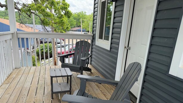 A wooden deck with a table and two chairs, a door, and a window.