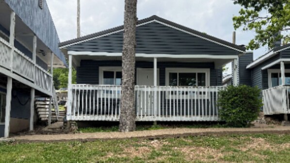 A single-story house with a porch, a white fence, and a tree in front. - Charming Cottage 1 at Alhonna Resort (Lake Ozark)