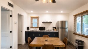A modern kitchen with a dining table, chairs, and a ceiling fan.