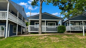 A row of two-story houses with balconies, a grassy yard, and a clear sky.