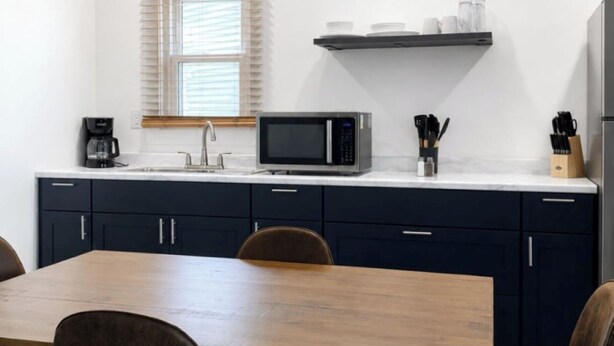A modern kitchen with dark cabinets, a microwave, and a coffee maker.