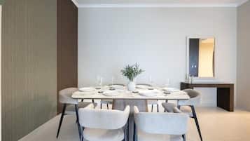 Un comedor moderno con una mesa rectangular dispuesta para cuatro personas, rodeada de sillas tapizadas.
