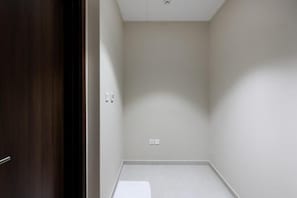 A room with a wooden door, white walls, and a tiled floor.
