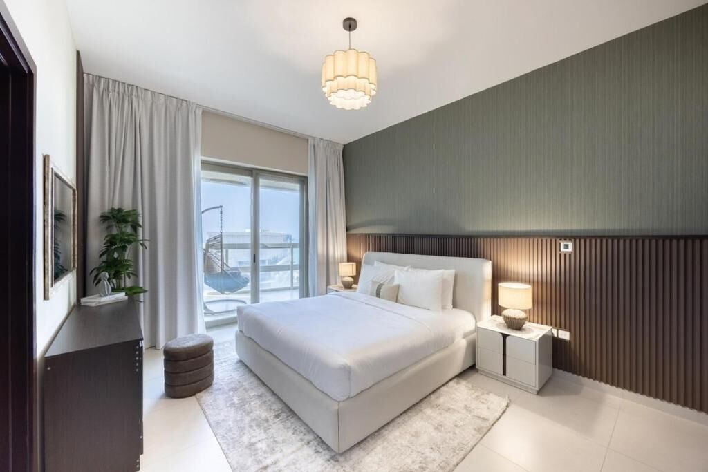 Ein modernes Schlafzimmer mit einem großen Bett, Nachttischlampen, Blick ins Freie und einer Deckenleuchte.