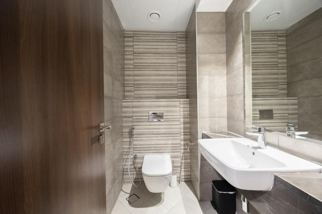 A modern bathroom with a toilet, bidet, and a large sink.